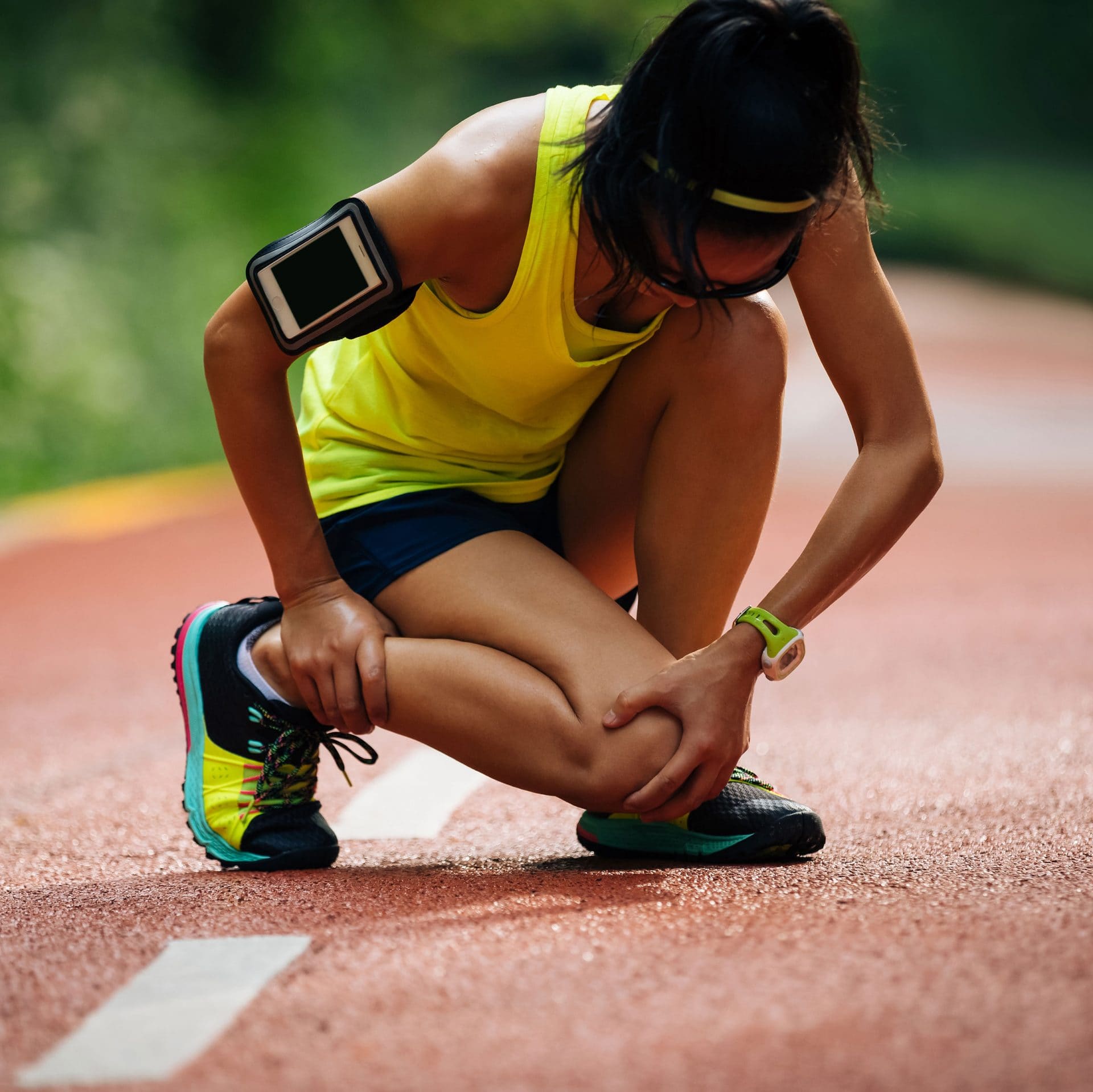 Hardloopster houdt haar onderbeen vast op de atletiekbaan