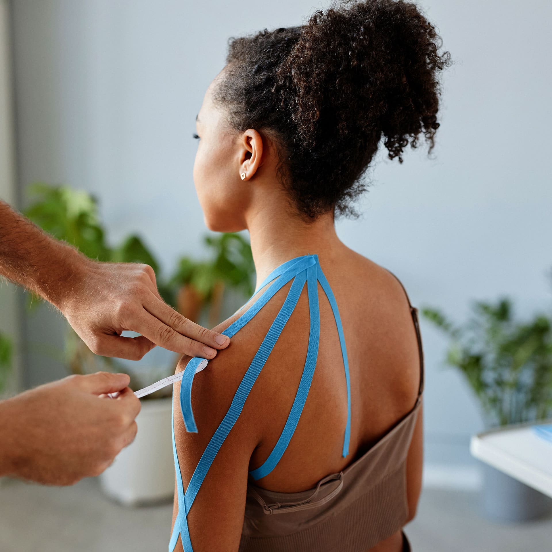 Blauwe kinesiotape wordt op een schouder aangebracht